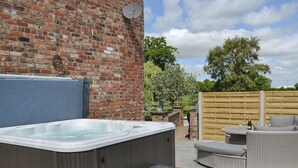 A hot tub with steps, a brick wall, and a wooden fence in a backyard setting. - Mulberry Cottage - CC253015 (Skerne, near Driffield)