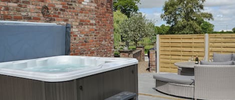 A hot tub with steps, a brick wall, and a wooden fence in a backyard setting.