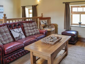 A cozy living room with a red leather sofa, a wooden coffee table, and a wicker basket.
