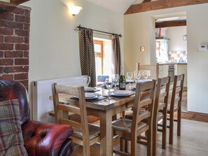 A dining area with a wooden table set for four, surrounded by wooden chairs. A red leather sofa is visible in the foreground.
