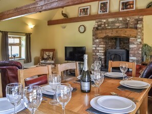 A dining area with a wooden table set for a meal, a fireplace, and a television in the background.