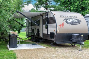 Un camping-car Grey Wolf doté d’un patio couvert, d’un barbecue et d’une table de pique-nique.