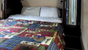 Una cama con un edredón colorido, una almohada blanca y un cabecero de madera oscura.