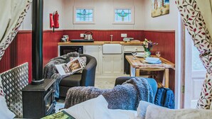 Una habitación acogedora con cama, una silla, una mesa, un hervidor y una chimenea.