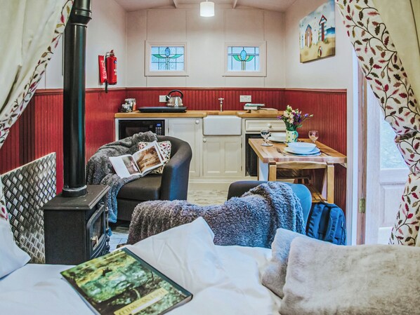 A cozy room with a bed, a chair, a table, a kettle, and a fire place.