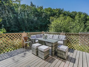 An outdoor patio with wicker furniture, a table, and a bottle of champagne.