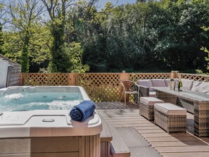 Un jacuzzi, mobiliario exterior y una terraza de madera con valla de celosía.