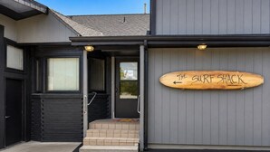 A building with a wooden sign reading 'THE SURF SHACK' and a set of steps leading to a door. - Surf Shack- North Muskegon Oasis (Muskegon)