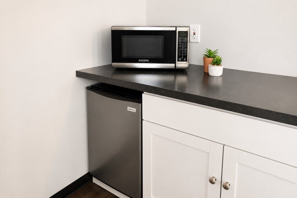 A kitchen with a microwave, a dishwasher, and a small potted plant on the countertop.