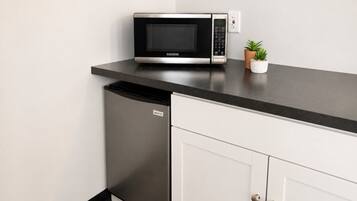 A kitchen with a microwave, a dishwasher, and a small potted plant on the countertop.