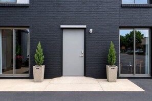 Edifici modern amb façana de maó fosc, una porta central i dues plantes a cada banda.