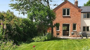 Ein zweistöckiges Backsteinhaus mit gepflegtem Rasen und Garten.