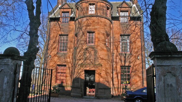 Ein großes, historisches Gebäude mit einem zentralen Turm, zahlreichen Fenstern und einem ehrwürdigen Eingangstor.