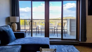 A room with a large sliding glass door leading to an outdoor patio with a view of a hilly landscape. - Luxe Downtown Winter Park Condo + Hot Tubs - 3 Full Baths -  Steps to Shuttle (Winter Park)