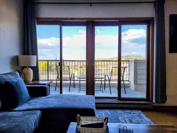 A room with a large sliding glass door leading to an outdoor patio with a view of a hilly landscape.