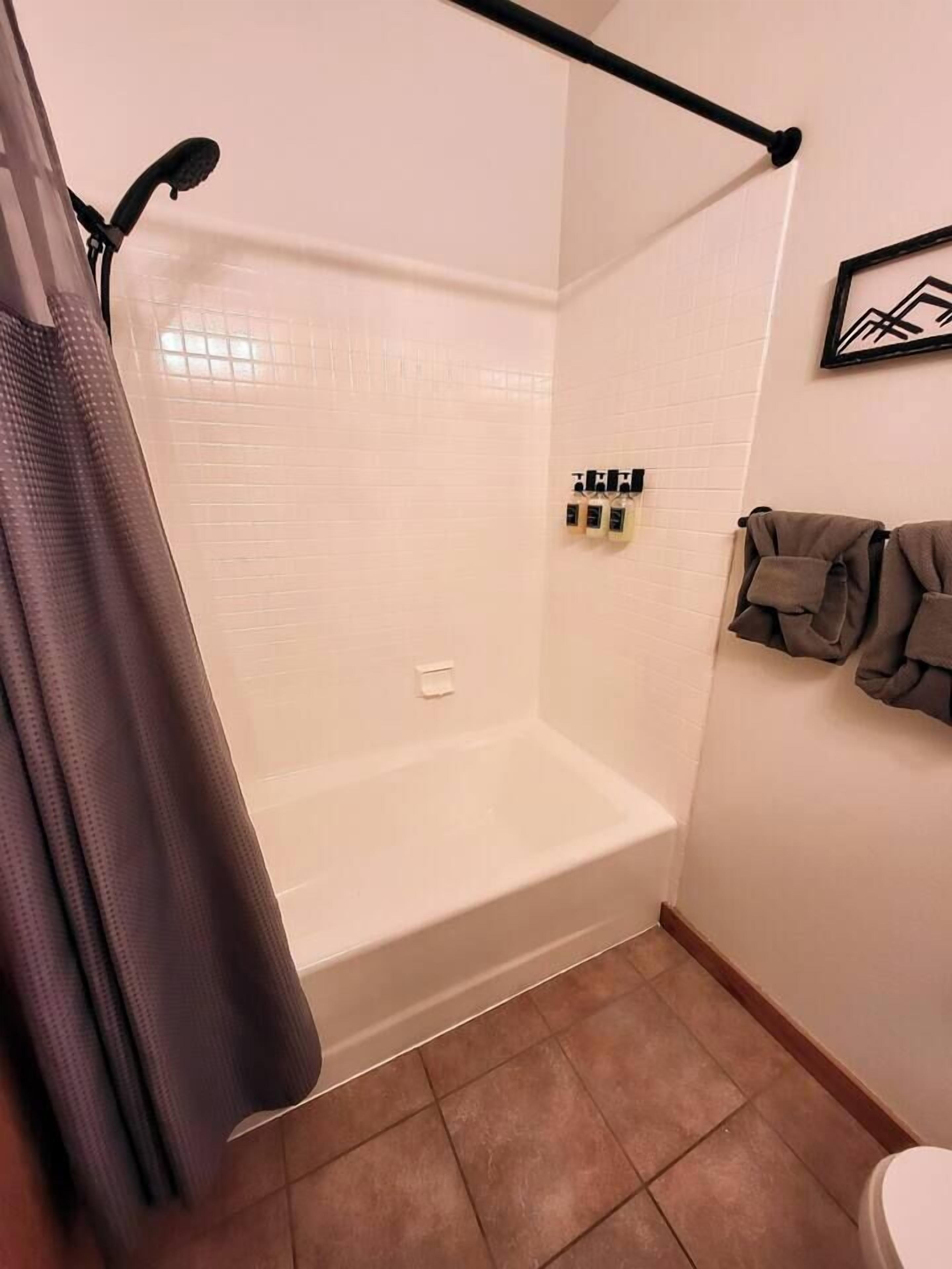 A bathroom with a shower, a toilet, and a towel rack.