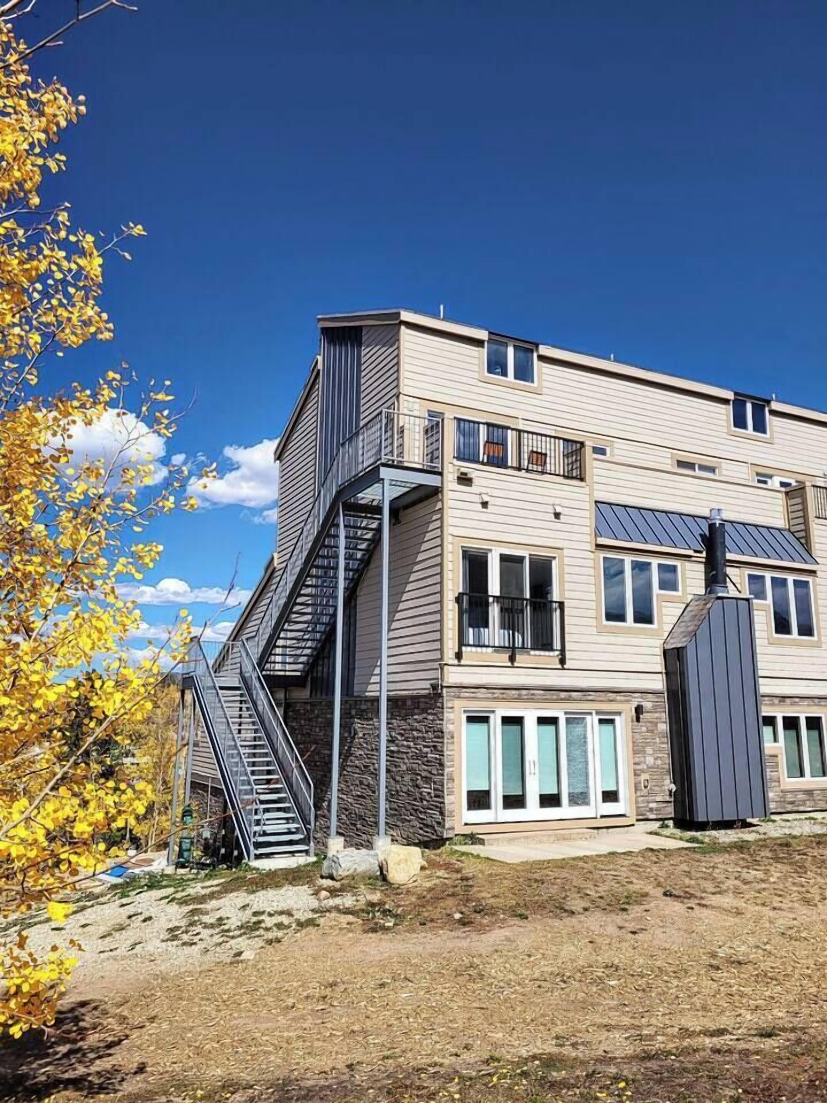 Un immeuble à plusieurs étages doté d’une architecture moderne, caractérisé par un escalier imposant, de grandes fenêtres et des panneaux solaires.