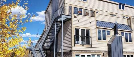 Un immeuble à plusieurs étages doté d’une architecture moderne, caractérisé par un escalier imposant, de grandes fenêtres et des panneaux solaires.