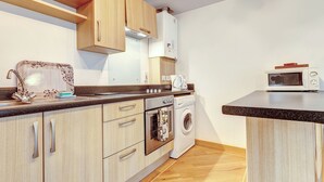 A kitchen with wooden cabinets, a microwave, a washing machine, and a sink with a decorative backsplash.