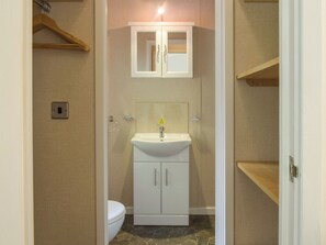 Ein kleines Badezimmer mit einem weißen Waschbecken, einem Spiegel und einer Toilette.