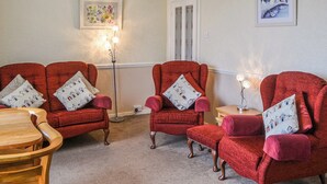 Une pièce avec trois fauteuils rouges, une table en bois et un lampadaire.