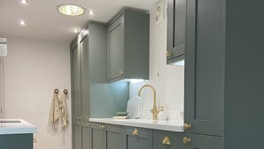 A modern kitchen with grey cabinets, gold handles, and a white countertop.