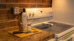 A kitchen with a granite countertop, a white stove, and a brick wall. - Incognito #3 : Ground Floor / 1 block from The Scotsman General Store (Laurel)