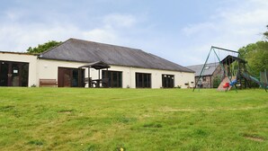 A building with a covered patio area, a swing set, and a lawn.