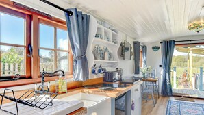 A kitchen with wooden cabinets, a sink, and a window with curtains.
