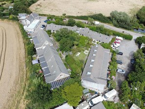 An aerial view of a residential area with multiple houses, a parking lot, and a field.