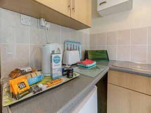 A kitchen counter with a coffee maker, toaster, and various food items. - 16 Beech Cottage-UK38936 (Lands End, near Porthcurno)