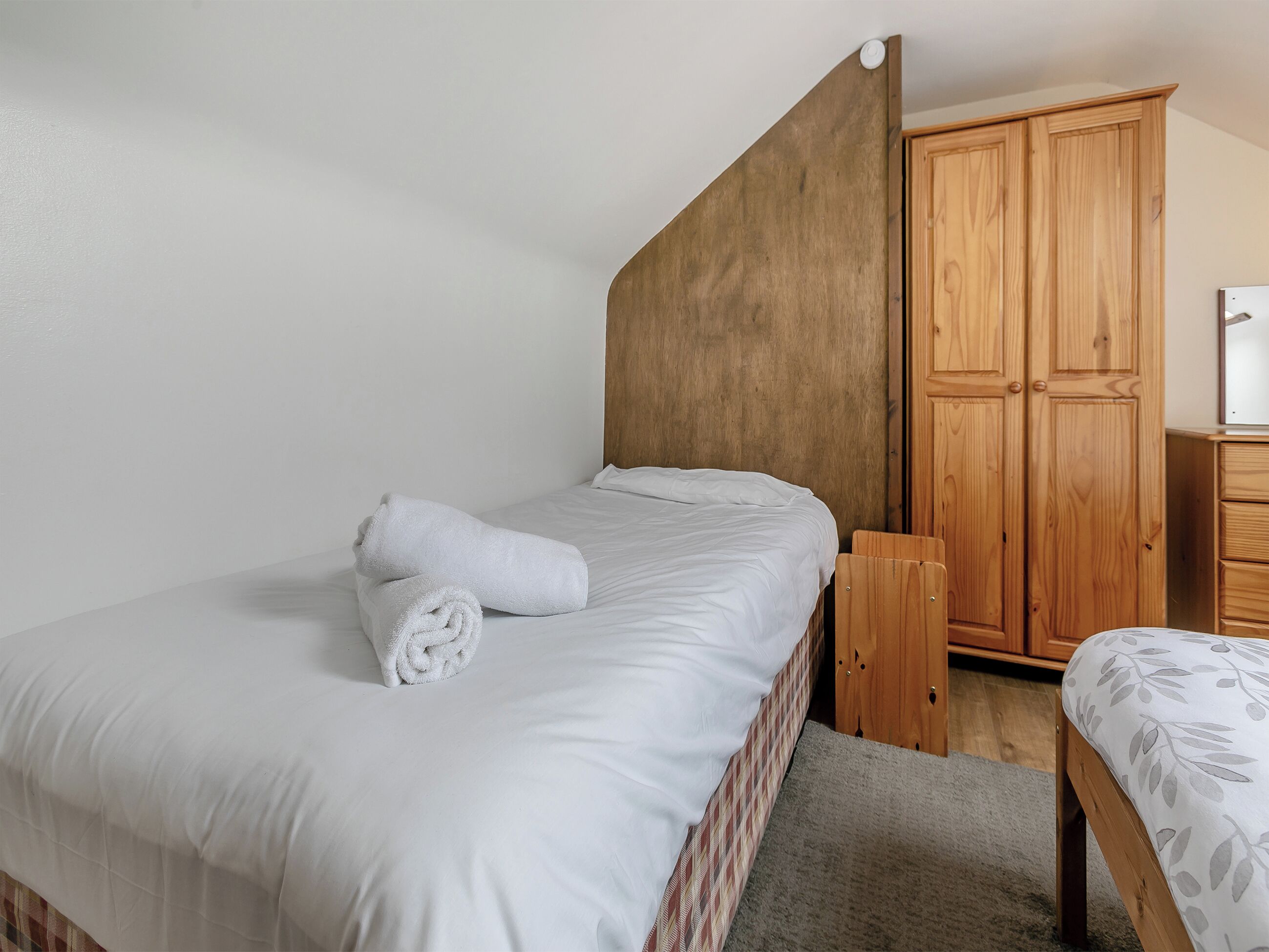 Un dormitorio con una cama, un armario de madera y una mesita de noche.