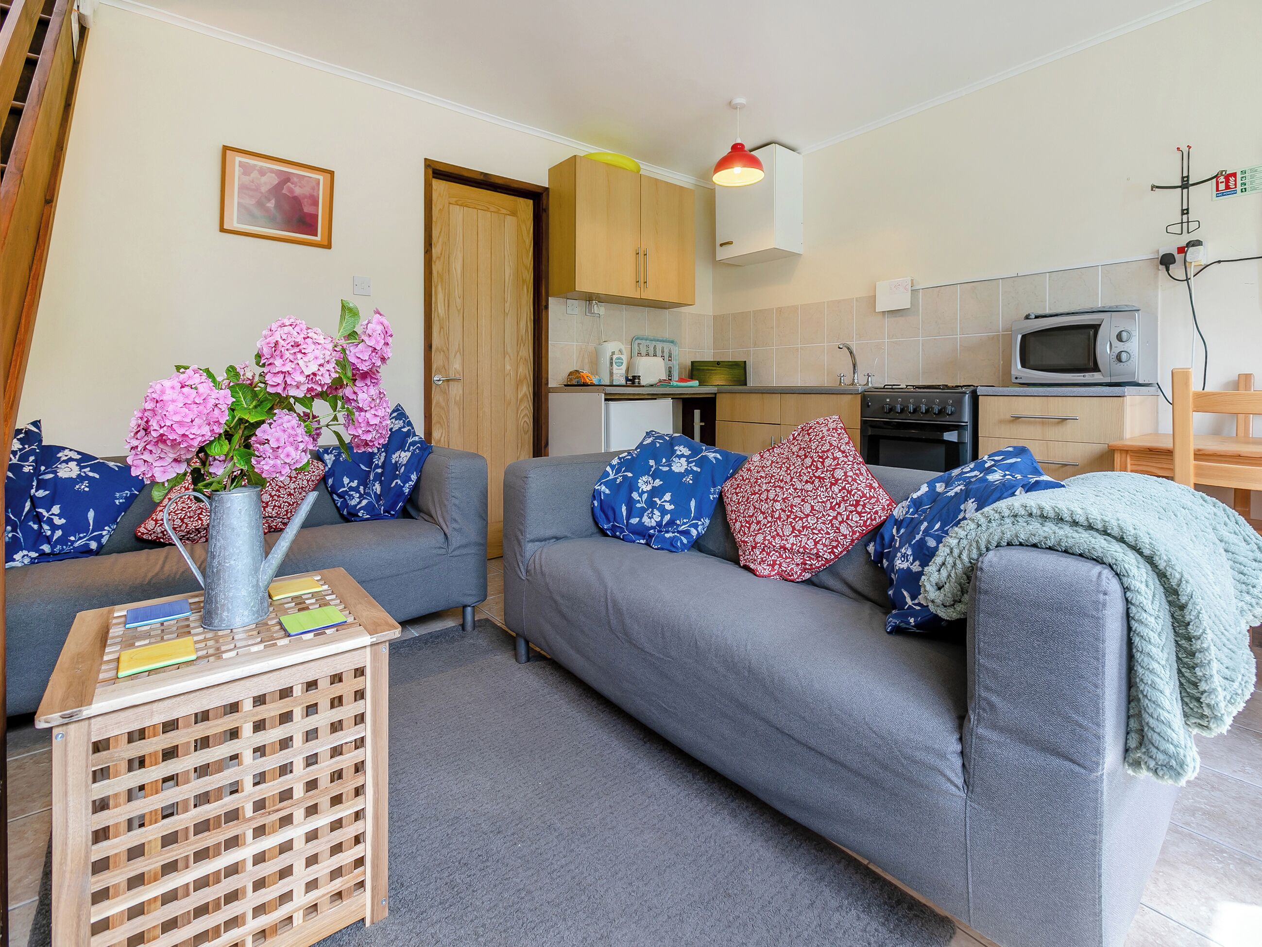 A living room with a grey sofa, a wooden coffee table, and a vase with pink flowers.