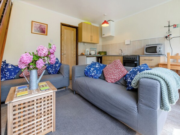 A living room with a grey sofa, a wooden coffee table, and a vase with pink flowers.