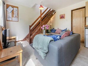 A living room with a sofa, a wooden TV stand, a staircase, and a wall-mounted bulletin board.