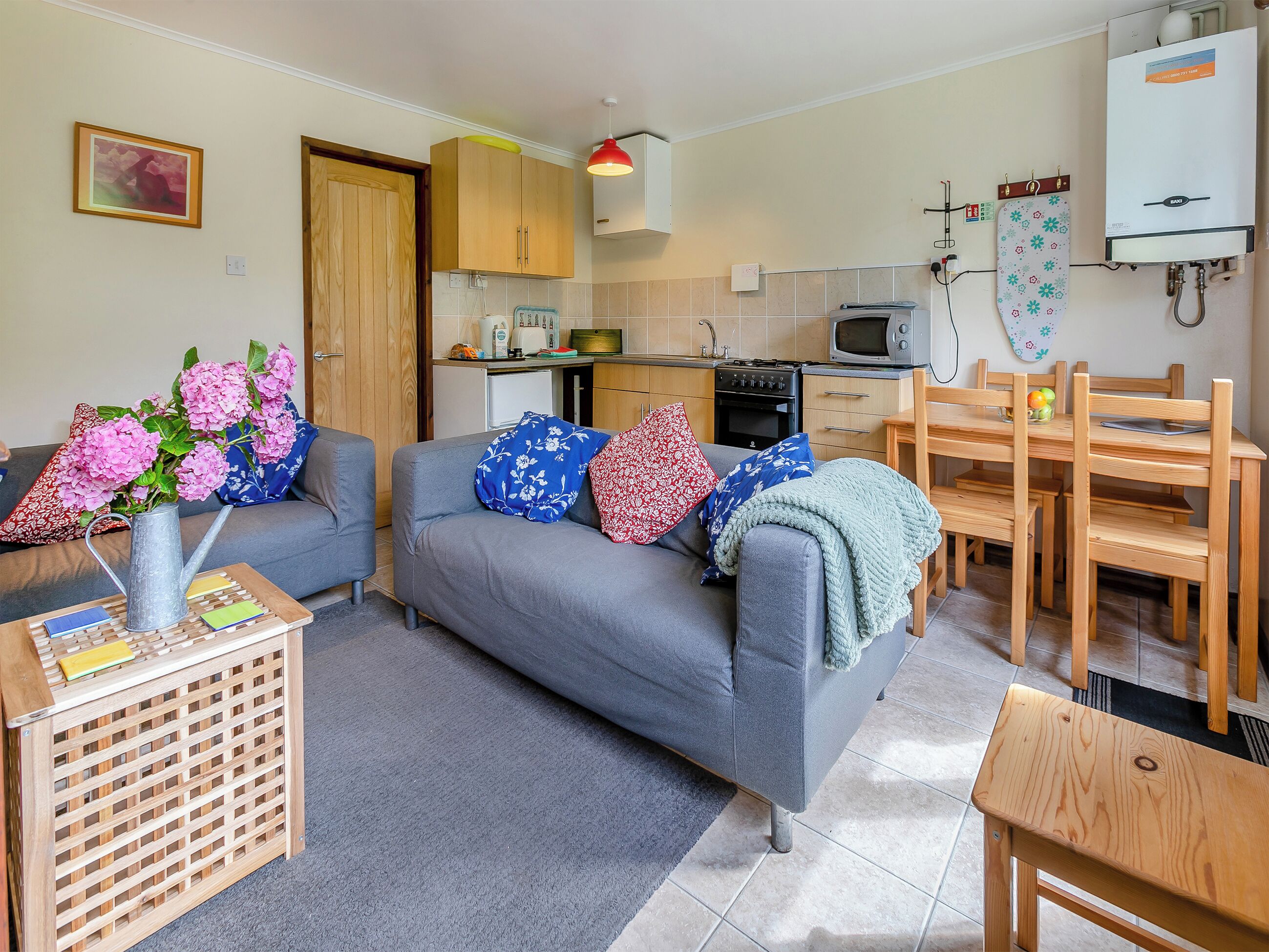 A compact living space with a sofa, a dining table, a kitchen area, and a water heater.