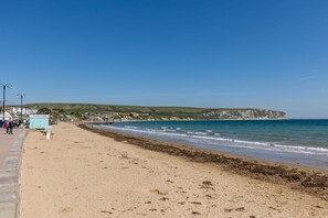 Enjoy a serene beachside stroll along the paved walkway, with the ocean's gentle waves and scenic cliff views.