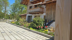 A wooden building with balconies, a paved driveway, and a sign indicating a parking area. - Cozy vacation apartment in the Isarwinkel (Gaißach)