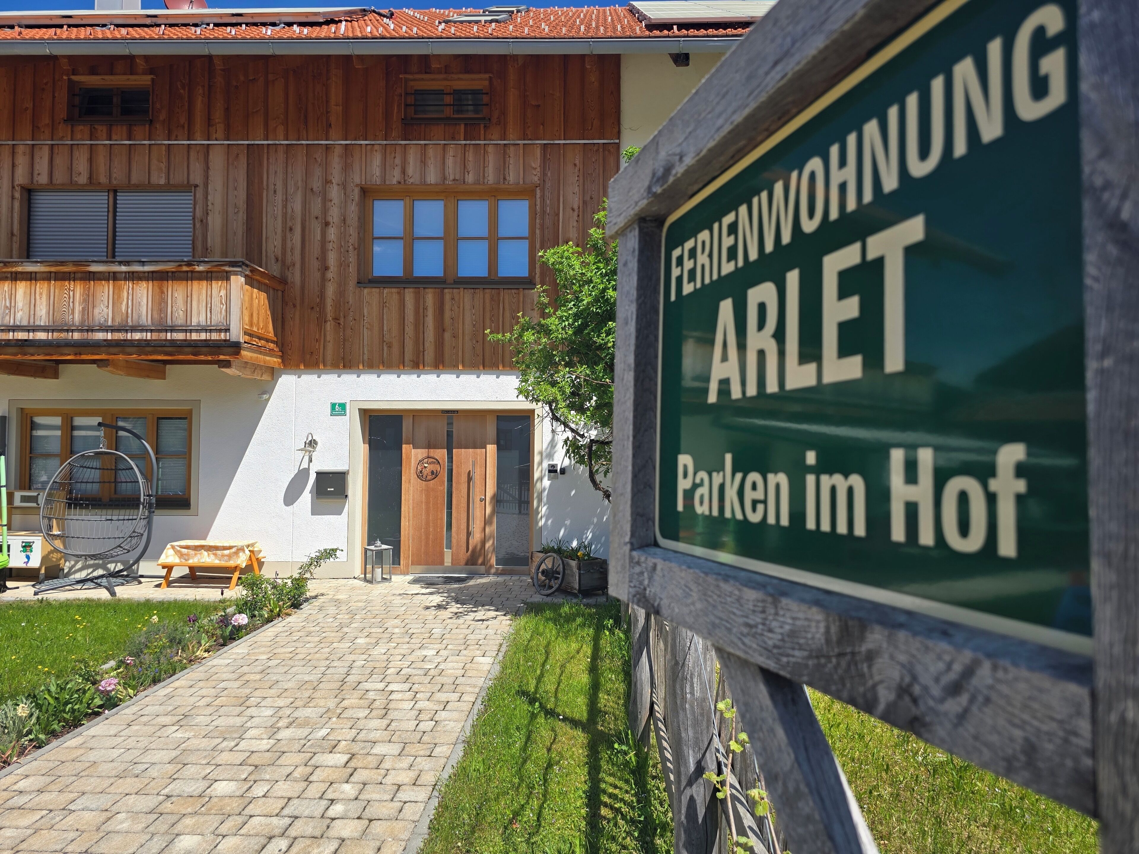 En træbygning med et skilt, der siger 'FERIENWOHNUNG ARLET Parken im Hof'.