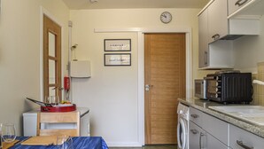 Een praktische keuken met een wasmachine, een magnetron, en een eethoek met een tafel gedekt voor twee personen.
