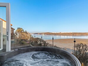 A hot tub with a view of a river and wind turbines in the distance. - 4 bedroom accommodation in Pembroke Dock (Pembroke Dock)