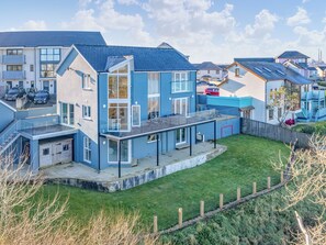 A modern residential building with a flat roof, large windows, and a fenced backyard. - 4 bedroom accommodation in Pembroke Dock (Pembroke Dock)