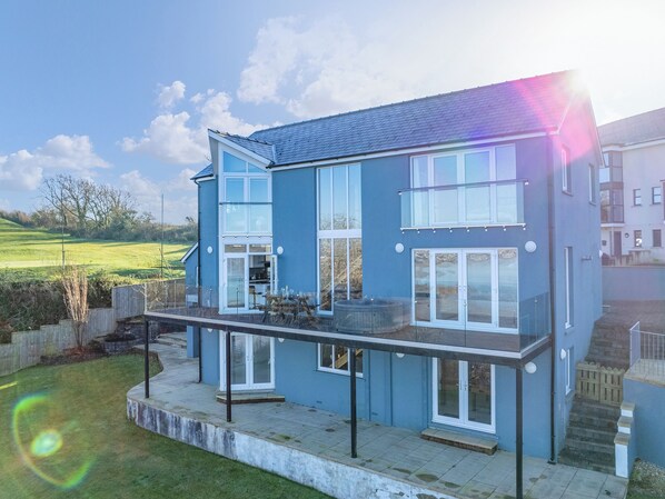 A two-story house with a balcony, large windows, and a view of a green landscape. - 4 bedroom accommodation in Pembroke Dock (Pembroke Dock)