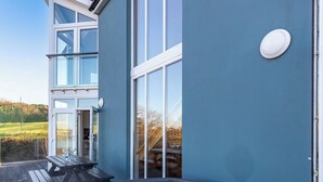Ein modernes Gebäude mit großen Fenstern, einem Whirlpool und einer Holzterrasse.