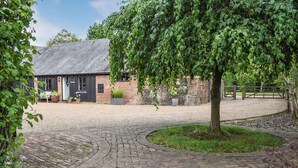 A rustic building with a brick exterior, a gravel driveway, and a tree in the foreground. - 1 bedroom accommodation in Hadlow Down (Hadlow Down)