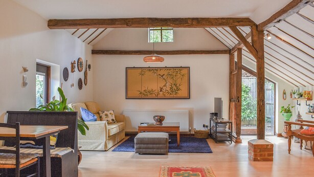 A spacious living room with a high ceiling, exposed wooden beams, a large window, and a traditional Japanese painting. - 1 bedroom accommodation in Hadlow Down (Hadlow Down)