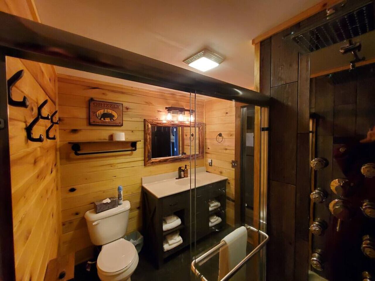 A wooden interior bathroom with a toilet, sink, and shower.