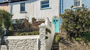 A coastal building with a stone staircase leading to a turquoise door, surrounded by greenery. - 2 bedroom accommodation in Brixham (Brixham)