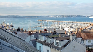 A coastal town with a marina, residential buildings, and a pier extending into the sea. - 2 bedroom accommodation in Brixham (Brixham)