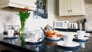 A kitchen with a marble countertop, white cabinets, a microwave, a toaster, and a vase with flowers.